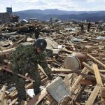 Rescue workers look for survivors while going through debris in Rikuzentakada People in Iwate Prefecture