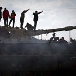 Libyans stood atop a wrecked tank belonging to loyalist forces on the outskirts of Benghazi