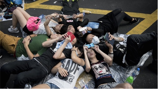 Hong Kong Demonstrations - group sleeping on street chatting on mobile