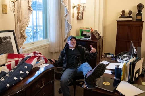 US Capitol Riot Photo - A Trump Supporter Sits Inside the Office of House Speaker Nancy Pelosi